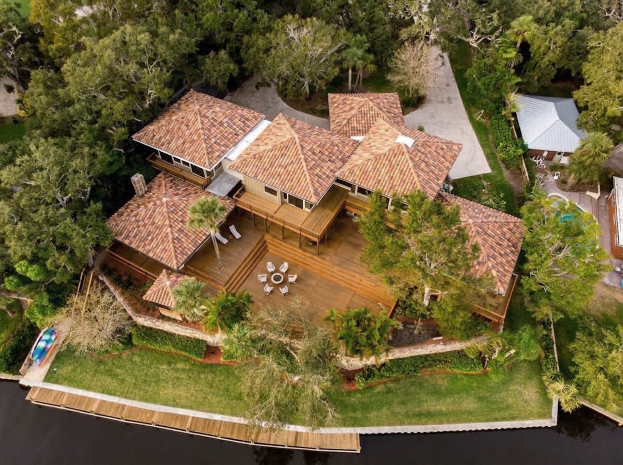 Aerial over a private lakefront dock with a kayak, real water and a real corridor.