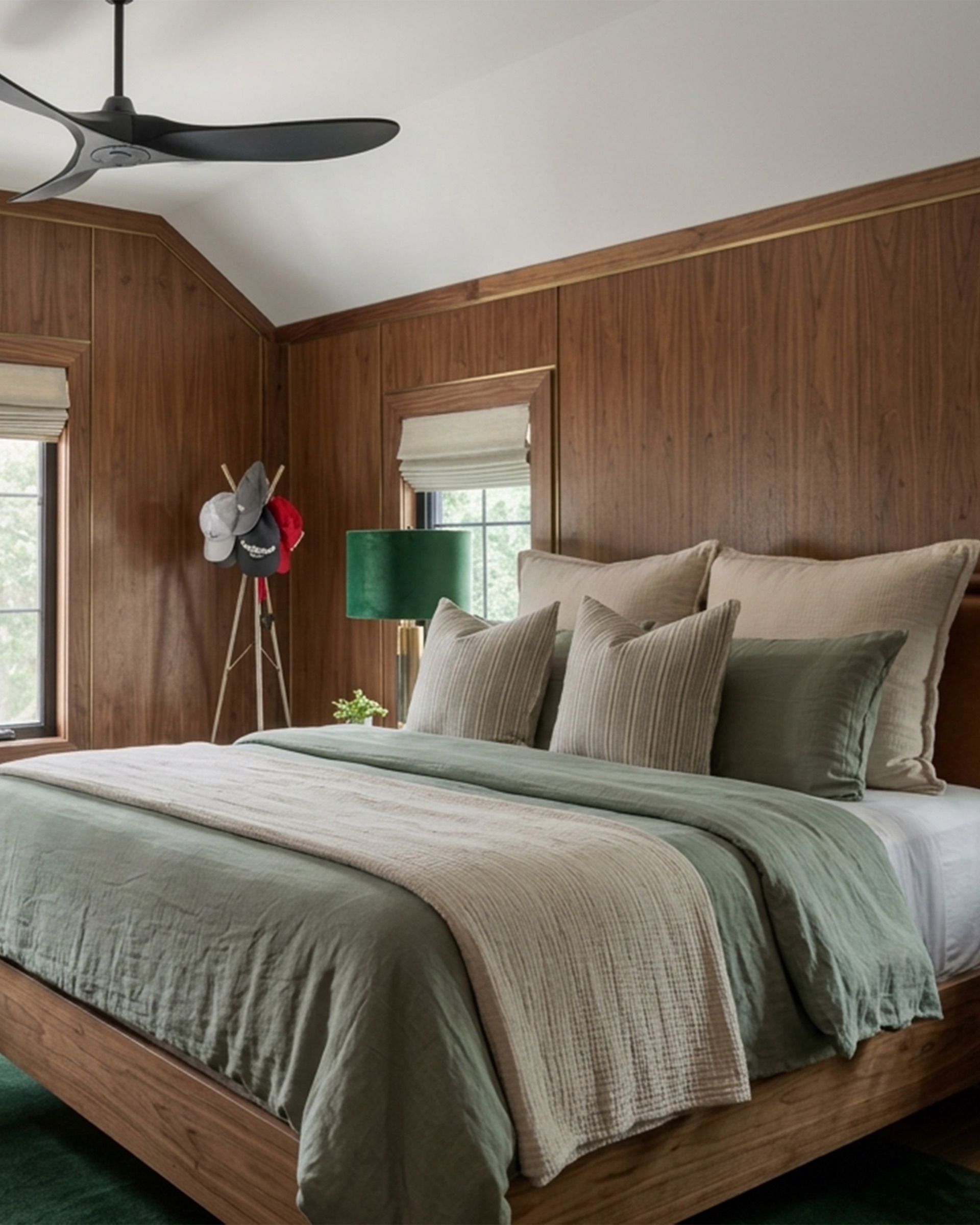 Walnut-paneled secondary bedroom, green velvet lamp, layered pillows.